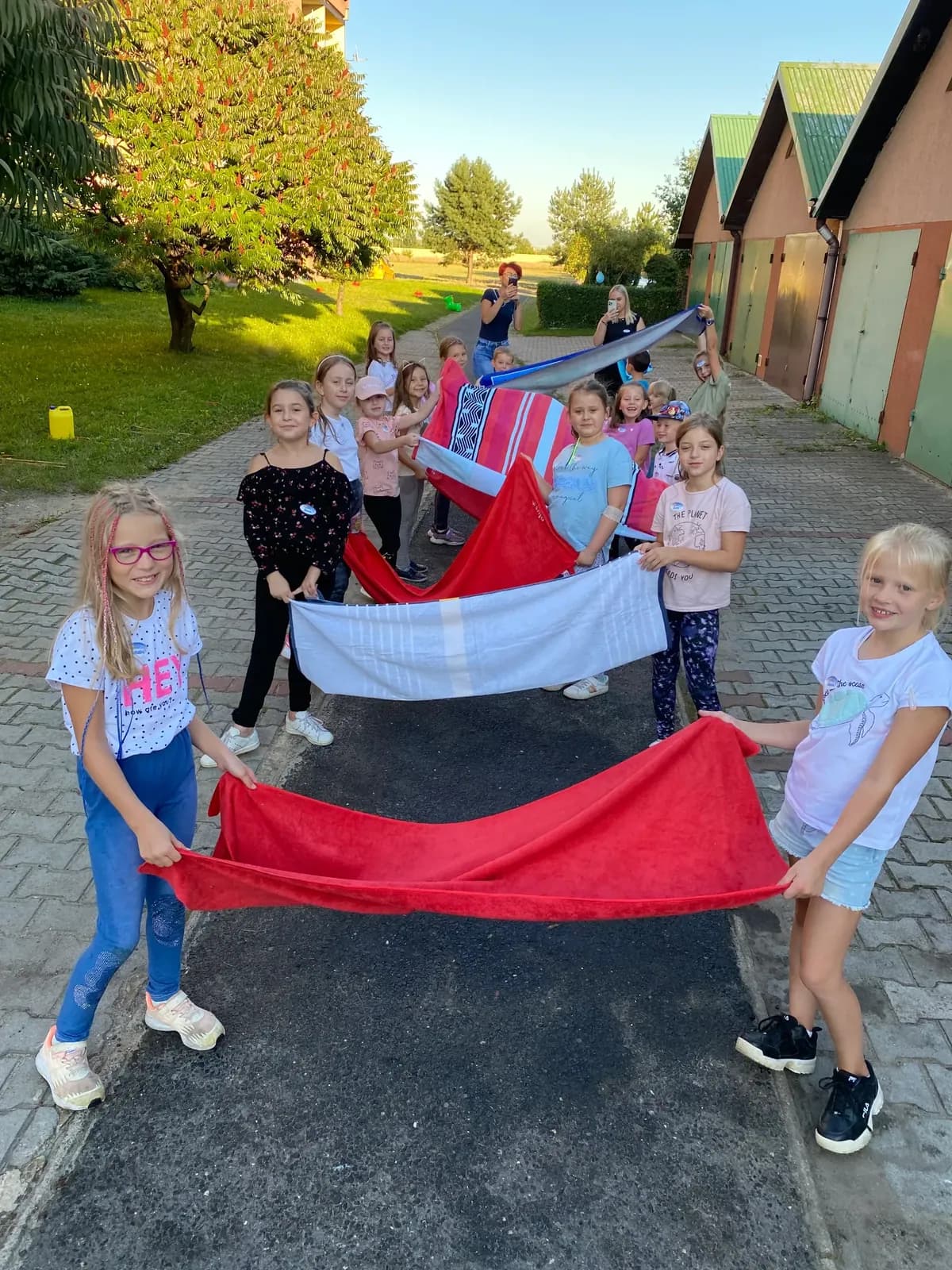 Dzieci z biało-czerwoną chustą animacyjną podczas gry w plenerze