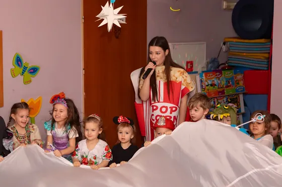 Animatorka z grupą przedszkolaków siedzących na chuście animacyjnej
