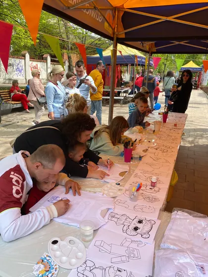 Stanowisko plastyczne pod namiotem na pikniku — rodziny malują z dziećmi