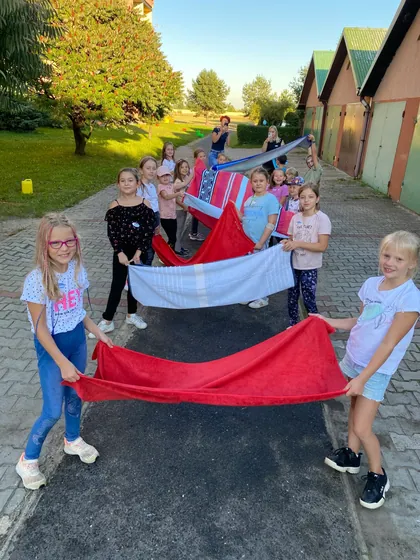 Dzieci z biało-czerwoną chustą animacyjną podczas gry w plenerze