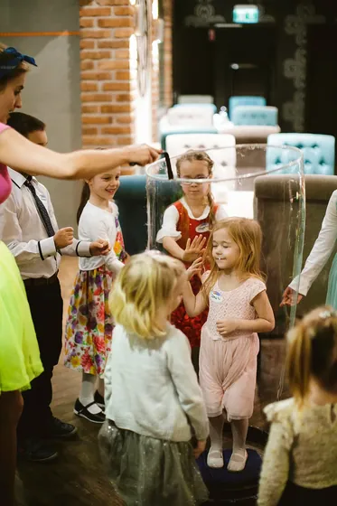 Dzieci bawią się w sali z ceglaną ścianą podczas przyjęcia